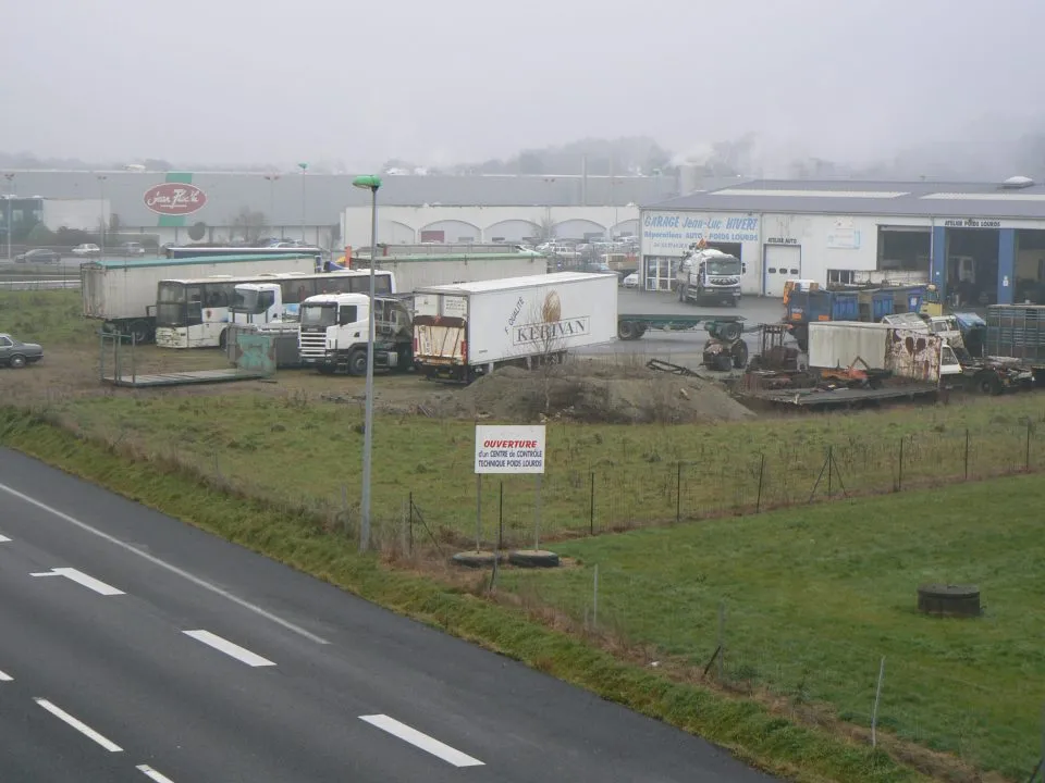 Zone industrielle avec camions et remorques stationnés.